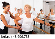 Dancing mature woman standing on a ballet stance, where the choreographer helps to perform the exercise. Стоковое фото, фотограф Яков Филимонов / Фотобанк Лори