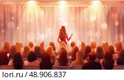 A woman stands confidently in front of a large crowd of diverse people, addressing them with a microphone. Стоковое AI-изображение, AI-художник Данила Большаков / Фотобанк Лори