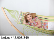 Studio shot of a woman in a straw hat lounging on a striped hammock. Стоковое фото, агентство Ingram Publishing / Фотобанк Лори