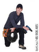 Handyman with power drill kneeling. Стоковое фото, агентство Ingram Publishing / Фотобанк Лори