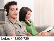 a woman reading and a young man listening music on a couch. Стоковое фото, агентство Ingram Publishing / Фотобанк Лори