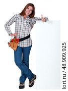 Handywoman standing next to a blank sign and giving the thumb’s up. Стоковое фото, агентство Ingram Publishing / Фотобанк Лори