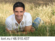 Dark haired man lying in filed. Стоковое фото, агентство Ingram Publishing / Фотобанк Лори