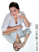 Woman drinking a glass of milk on a mirrored table. Стоковое фото, агентство Ingram Publishing / Фотобанк Лори