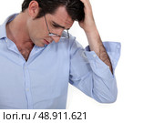 young businessman looking tired with glasses lowered and hand to his head. Стоковое фото, агентство Ingram Publishing / Фотобанк Лори