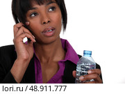 A black businesswoman on the phone waiting to take a sip. Стоковое фото, агентство Ingram Publishing / Фотобанк Лори