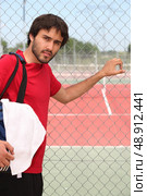 Young man outside a tennis court. Стоковое фото, агентство Ingram Publishing / Фотобанк Лори