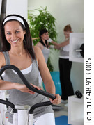 Smiling brown-haired woman on cross trainer. Стоковое фото, агентство Ingram Publishing / Фотобанк Лори