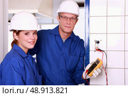 an electrician and his female colleague checking an electrical outlet. Стоковое фото, агентство Ingram Publishing / Фотобанк Лори