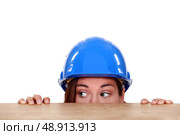 Tradeswoman peeping out from beneath a table. Стоковое фото, агентство Ingram Publishing / Фотобанк Лори