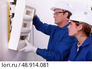 Electrician and apprentice mounting electric meter. Стоковое фото, агентство Ingram Publishing / Фотобанк Лори