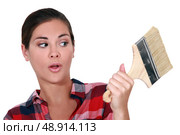 A female painter looking at a brush with a dubious look. Стоковое фото, агентство Ingram Publishing / Фотобанк Лори