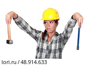 Apprehensive tradeswoman holding a hammer and chisel. Стоковое фото, агентство Ingram Publishing / Фотобанк Лори