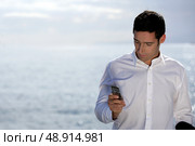 Man sending an SMS by the water’s edge. Стоковое фото, агентство Ingram Publishing / Фотобанк Лори