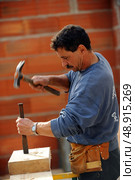 Worker using chisel and hammer on large block of wood. Стоковое фото, агентство Ingram Publishing / Фотобанк Лори