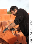Mason making adjustments to brick. Стоковое фото, агентство Ingram Publishing / Фотобанк Лори