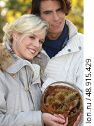 couple dressed in warm clothes,  woman is holding a wickerwork basket full of chestnuts. Стоковое фото, агентство Ingram Publishing / Фотобанк Лори