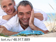 Couple laid on towel at the beach. Стоковое фото, агентство Ingram Publishing / Фотобанк Лори