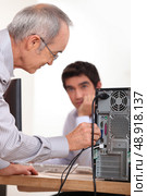 Man plugging a cable into the back of a hard drive. Стоковое фото, агентство Ingram Publishing / Фотобанк Лори