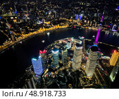 Shanghai, China - 1 April 2025: Aerial night view of Lujiazui and the Bund from Shanghai Tower with city lights, Huangpu River, and Oriental Pearl Tower. Редакционное фото, фотограф Татьяна Терехина / Фотобанк Лори