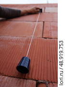 Bricklayer using a plumb line. Стоковое фото, агентство Ingram Publishing / Фотобанк Лори