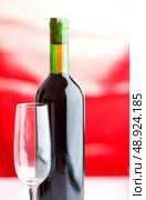 Bottle and wine glass on red background. Стоковое фото, агентство Ingram Publishing / Фотобанк Лори