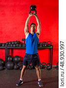 Kettlebell swing workout training man at gym with red walls. Стоковое фото, агентство Ingram Publishing / Фотобанк Лори
