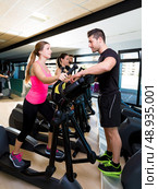 Aerobics elliptical walker trainer personal trainer man at fitness gym workout. Стоковое фото, агентство Ingram Publishing / Фотобанк Лори