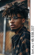 A close-up portrait of a young man with dreadlocks wearing glasses and a plaid shirt outdoors. Стоковое AI-изображение, AI-художник Данила Большаков / Фотобанк Лори
