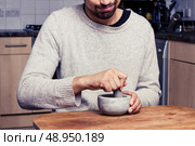 Young man grinding spices in kitchen. Стоковое фото, агентство Ingram Publishing / Фотобанк Лори