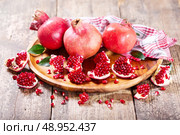 fresh pomegranates on wooden plate. Стоковое фото, агентство Ingram Publishing / Фотобанк Лори