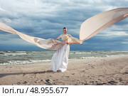 Incredible portrait of model with extremely long dress at the beach. Outdoors. Стоковое фото, агентство Ingram Publishing / Фотобанк Лори
