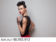 Pin Up style woman holding round sunglasses posing in red skirt. Red lips. Updo, twisted high bun. top knot. Стоковое фото, агентство Ingram Publishing / Фотобанк Лори