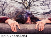 A young woman is hiding behind a wooden beam in the park. Стоковое фото, агентство Ingram Publishing / Фотобанк Лори