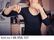 A disgusted young woman is holding a dead mouse by it’s tail in the kitchen. Стоковое фото, агентство Ingram Publishing / Фотобанк Лори