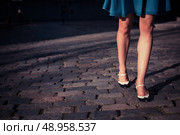 A young woman wearing a skirt and retro shoes is walking on a cobbled street at sunset. Стоковое фото, агентство Ingram Publishing / Фотобанк Лори