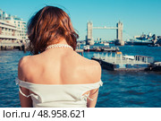 A young woman is tanning her back on a sunny day and looking at the river Thames in London, England. Стоковое фото, агентство Ingram Publishing / Фотобанк Лори