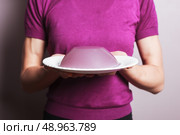 A young woman wearing a purple top is holding a plate with a pudding on it. Стоковое фото, агентство Ingram Publishing / Фотобанк Лори
