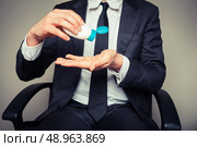 A businessman is squeezing a tube of sun screen. Стоковое фото, агентство Ingram Publishing / Фотобанк Лори