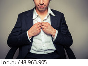 Young businessman sitting in office chair is buttoning his shirt. Стоковое фото, агентство Ingram Publishing / Фотобанк Лори