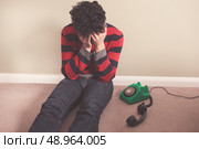 Sad man sitting on the floor has received bad news on the telephone. Стоковое фото, агентство Ingram Publishing / Фотобанк Лори