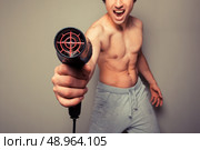 Athletic young man is holding a hair dryer and messing around with it. Стоковое фото, агентство Ingram Publishing / Фотобанк Лори