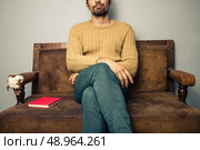 Young man sitting on sofa with a book he’s read. Стоковое фото, агентство Ingram Publishing / Фотобанк Лори