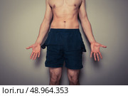 Athletic young man with empty pockets cannot afford to go to the gym. Стоковое фото, агентство Ingram Publishing / Фотобанк Лори
