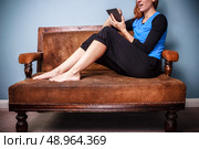 Young woman sitting on a sofa and reading on tablet. Стоковое фото, агентство Ingram Publishing / Фотобанк Лори