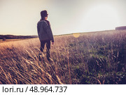 Woman standing in a field at sunset. Стоковое фото, агентство Ingram Publishing / Фотобанк Лори