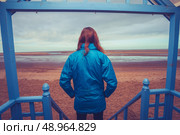 Woman standing outside beach hut in the winter. Стоковое фото, агентство Ingram Publishing / Фотобанк Лори