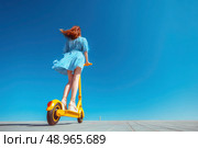 A woman is riding a yellow scooter on a sunny day. Стоковое AI-изображение, AI-художник Ярославский Максим / Фотобанк Лори