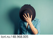 A cowboy is hiding behind his hat. Стоковое фото, агентство Ingram Publishing / Фотобанк Лори
