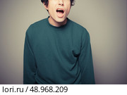 A young man is gesturing and pulling silly faces. Стоковое фото, агентство Ingram Publishing / Фотобанк Лори